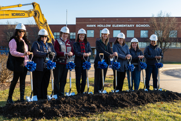  8 women pose with white hard hats and shovels 